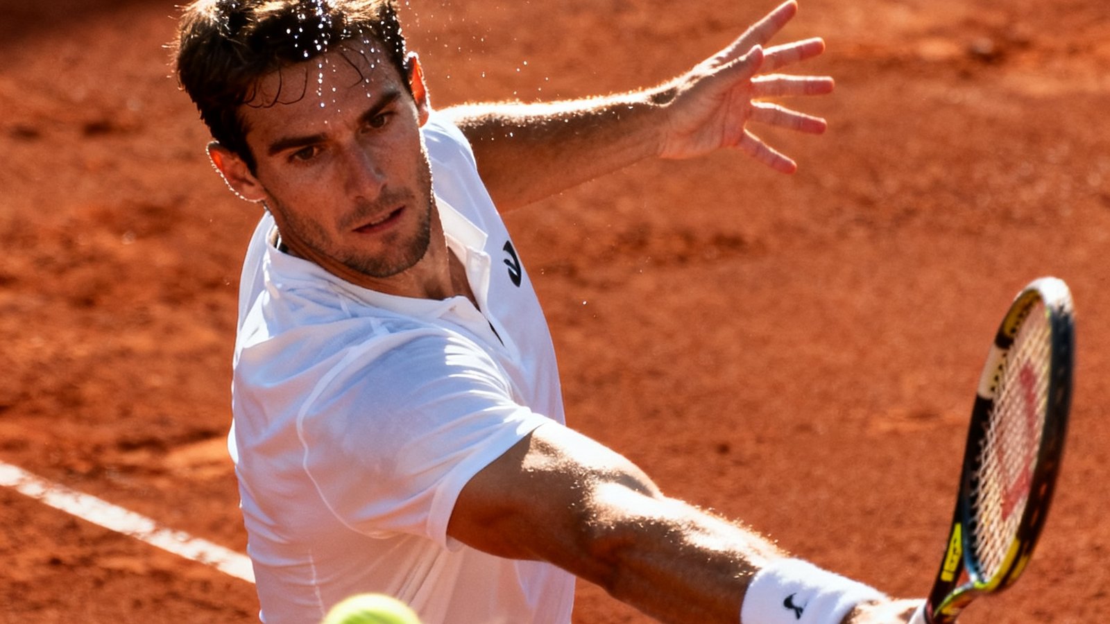 红土网球场上，一位身穿白色运动服的选手在底线打出精准的单手反拍，汗水从额头飞洒，手臂肌肉线条在阳光下清晰可见
